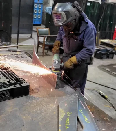 a man wearing a mask and welding gear using a grinder